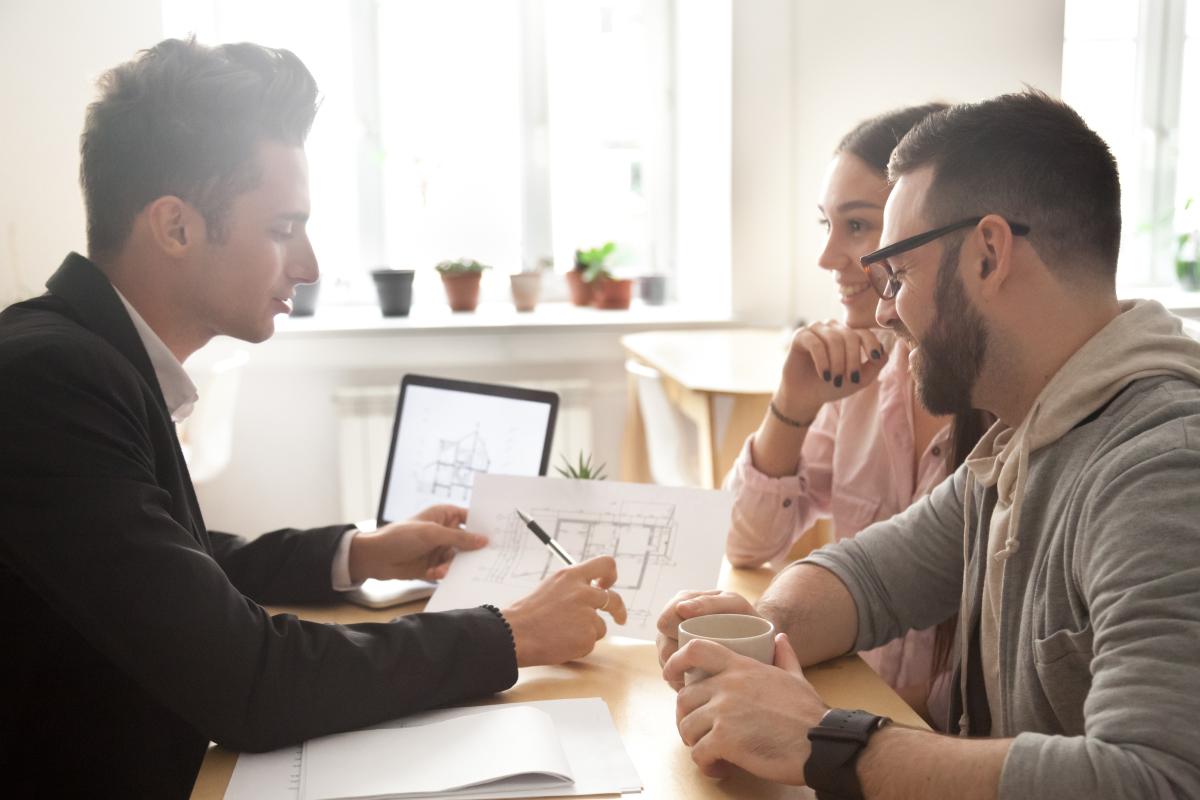 appartement invendu programme neuf – un courtier immobilier montre le plan d’un logement à un couple