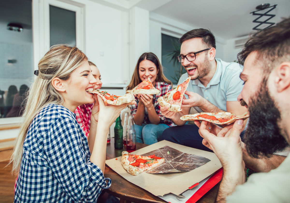 Loi Pinel et colocation – Groupe de jeunes colocataires en train de manger une pizza dans leur appartement