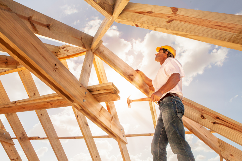 construction neuve - un ouvrier sur un chantier de construction installant le toit d'une maison