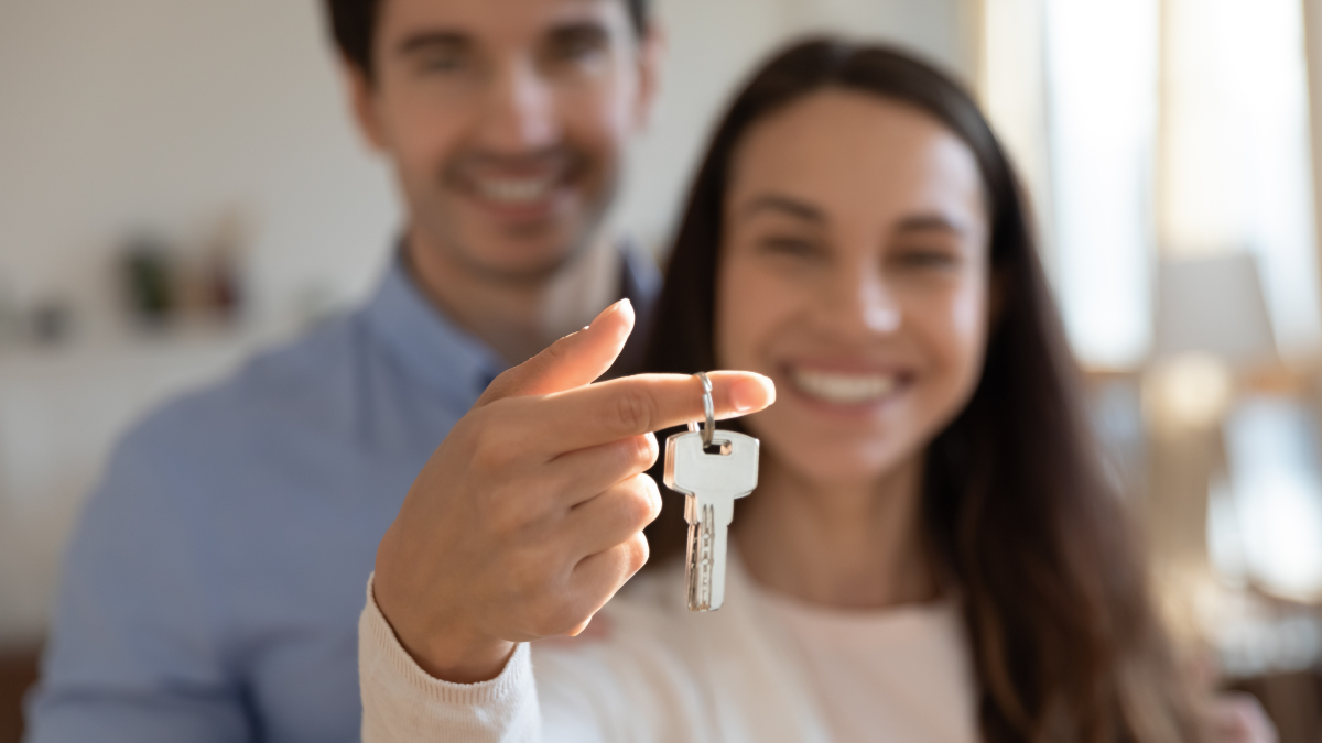 Faites confiance à nos courtiers immobiliers pour trouver votre futur logement Quartier Amédée Saint-Germain Bordeaux — un couple heureux qui sourit en tendant une paire de clés vers l’objectif
