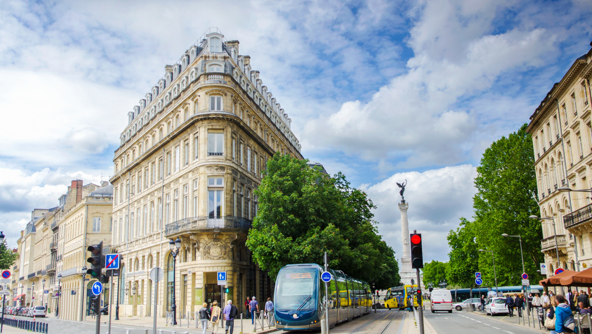 Loi Climat et Résilience à Bordeaux – Vue d’une rue bordelaise bordée d’arbres avec tram et immeubles anciens