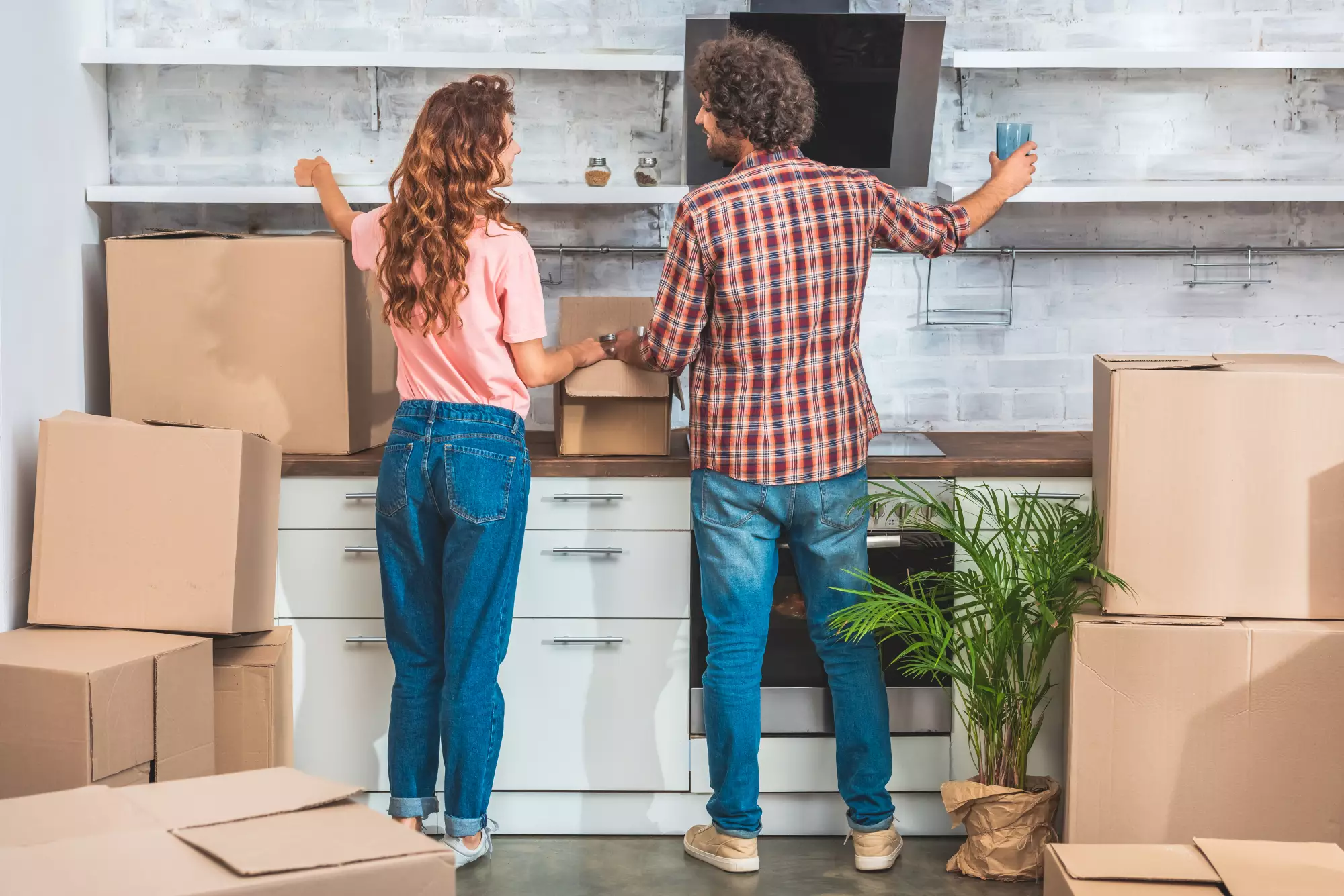 Vue de dos d'un couple s'installant dans le logement qu'il vient d'acheter