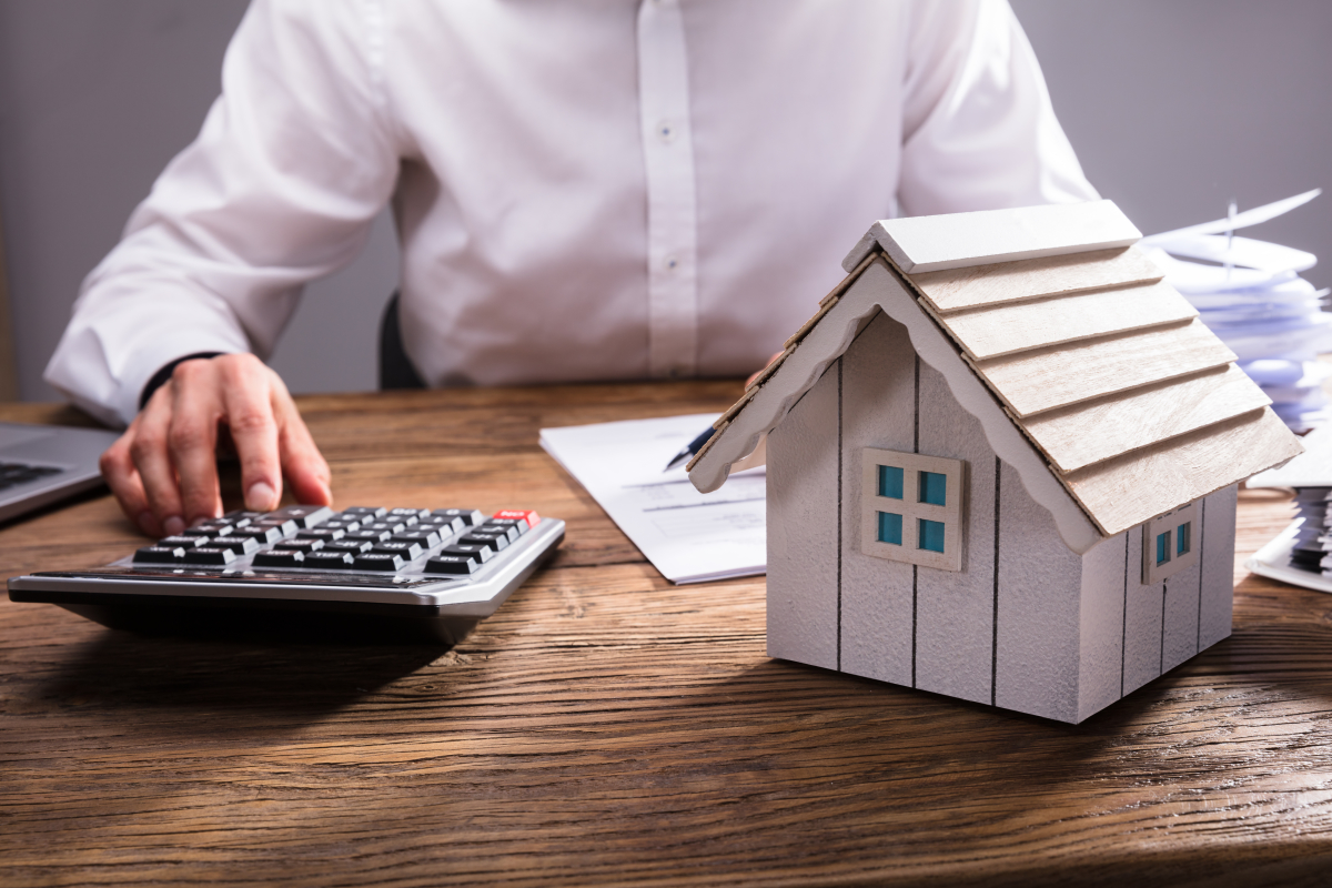 Assurance emprunteur – un homme est face à une calculatrice et une maison miniature