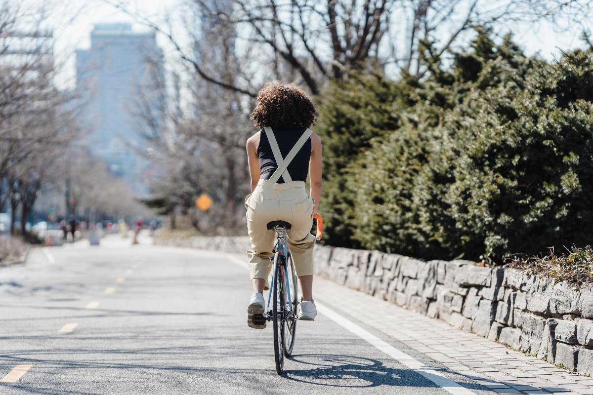 L’objectif des élus bordelais et d’améliorer de cadre de vie en mettant les végétaux au cœur du projet Permis de végétaliser Bordeaux – Une femme de dos faisant du vélo dans un environnement urbain