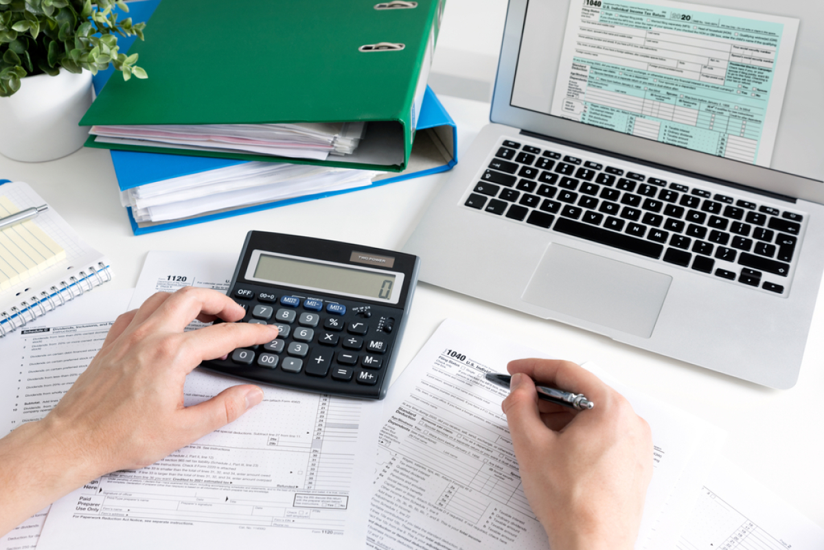  une personne calcule ses frais pour son projet immobilier avec une calculette et un ordinateur