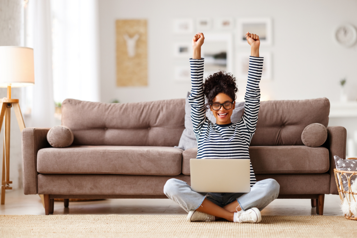Loi Pinel sous location — une femme sur son ordinateur lève les bras en l’air en signe de satisfaction