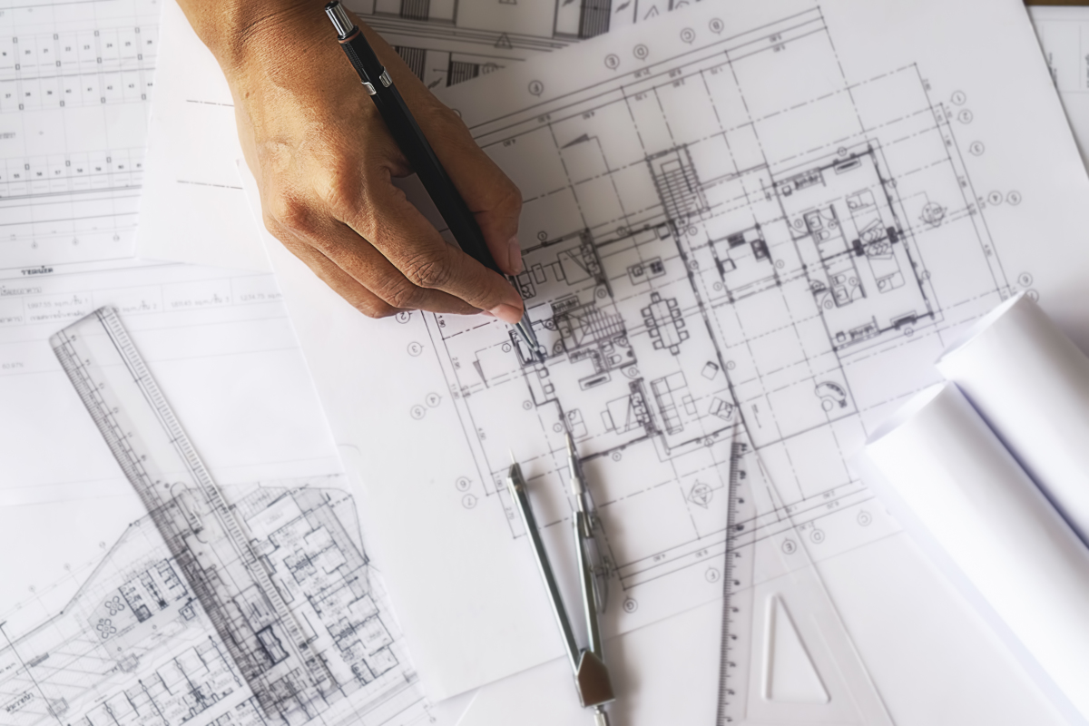 Passer par un architecte est la garantie d'un projet unique et sur mesure Un architecte en train de dessiner sur un plan