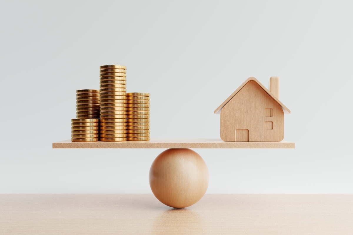 L'investissement en SCPI présente à la fois des avantages et des inconvénients Faut-il investir en SCPI – Une maison miniature et des piles de pièces en équilibre sur un balancier