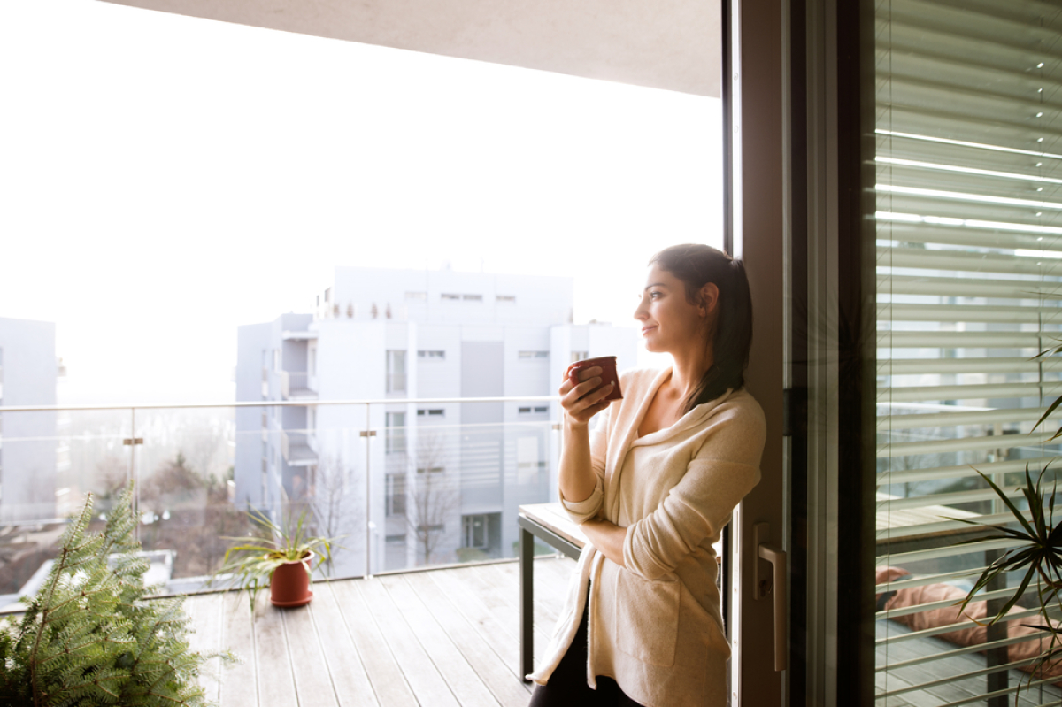 synthèse logement neuf 2022 – une femme profite de la terrasse de son logement neuf