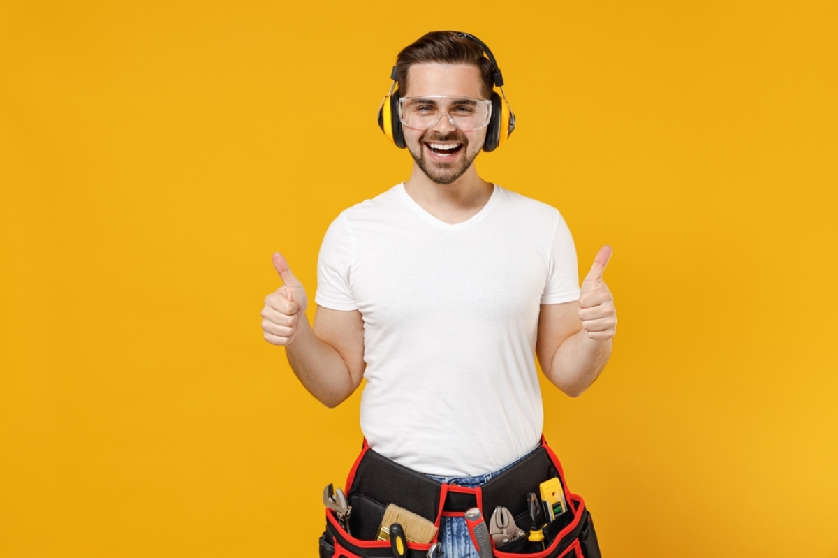un artisan du bâtiment avec un casque anti-bruit sur fond jaune