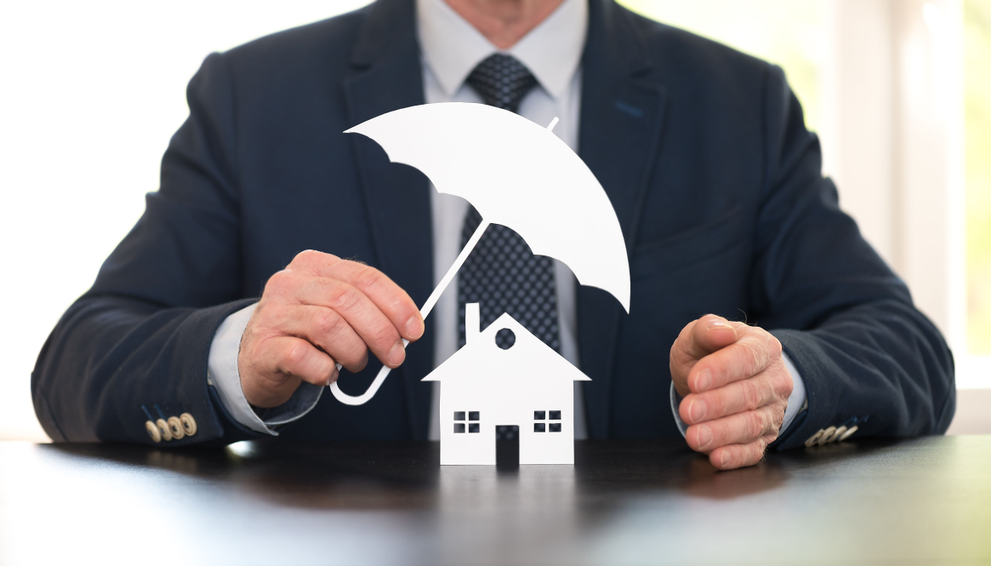 Un homme tient un parapluie au-dessus d'une maison