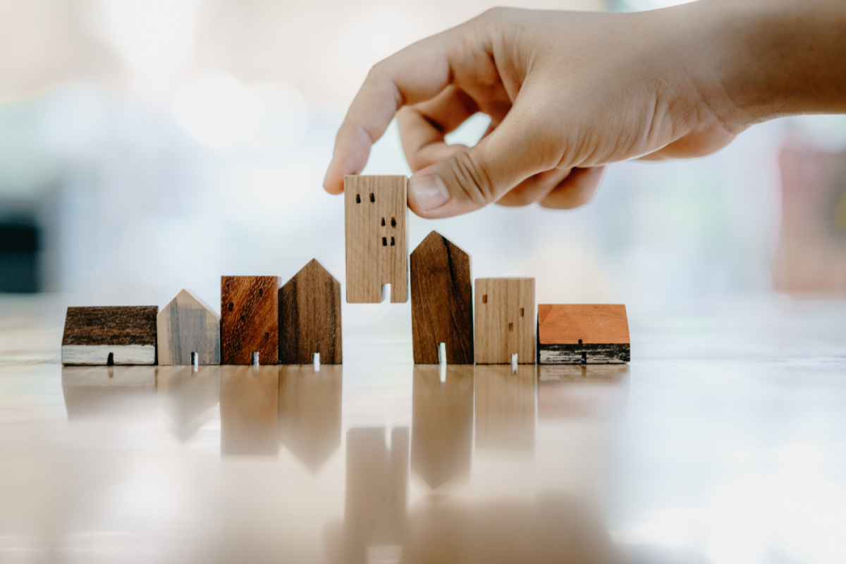La part minimum de logements sociaux dans le parc immobilier doit être de 20% bordeaux investit 20M pour les logements sociaux – un homme pose une figurine immeuble au milieu d’autres figurines maisons