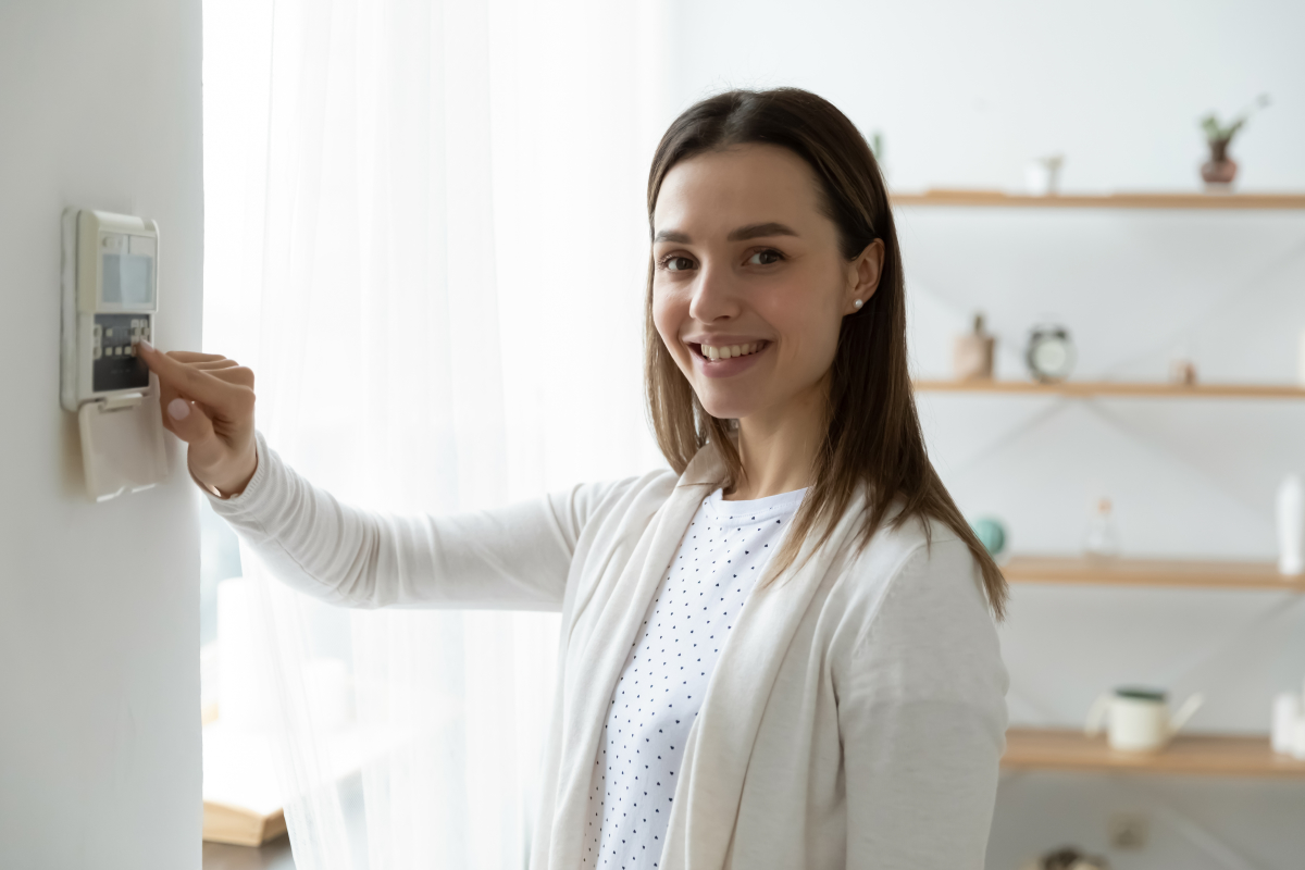 RE2020 – une femme règle son thermostat d’ambiance