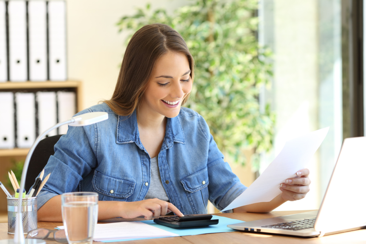 Beaucoup de ménages sont éligibles au PTZ Prolongement PTZ – Une femme qui sourit en faisant des calculs et tenant un document