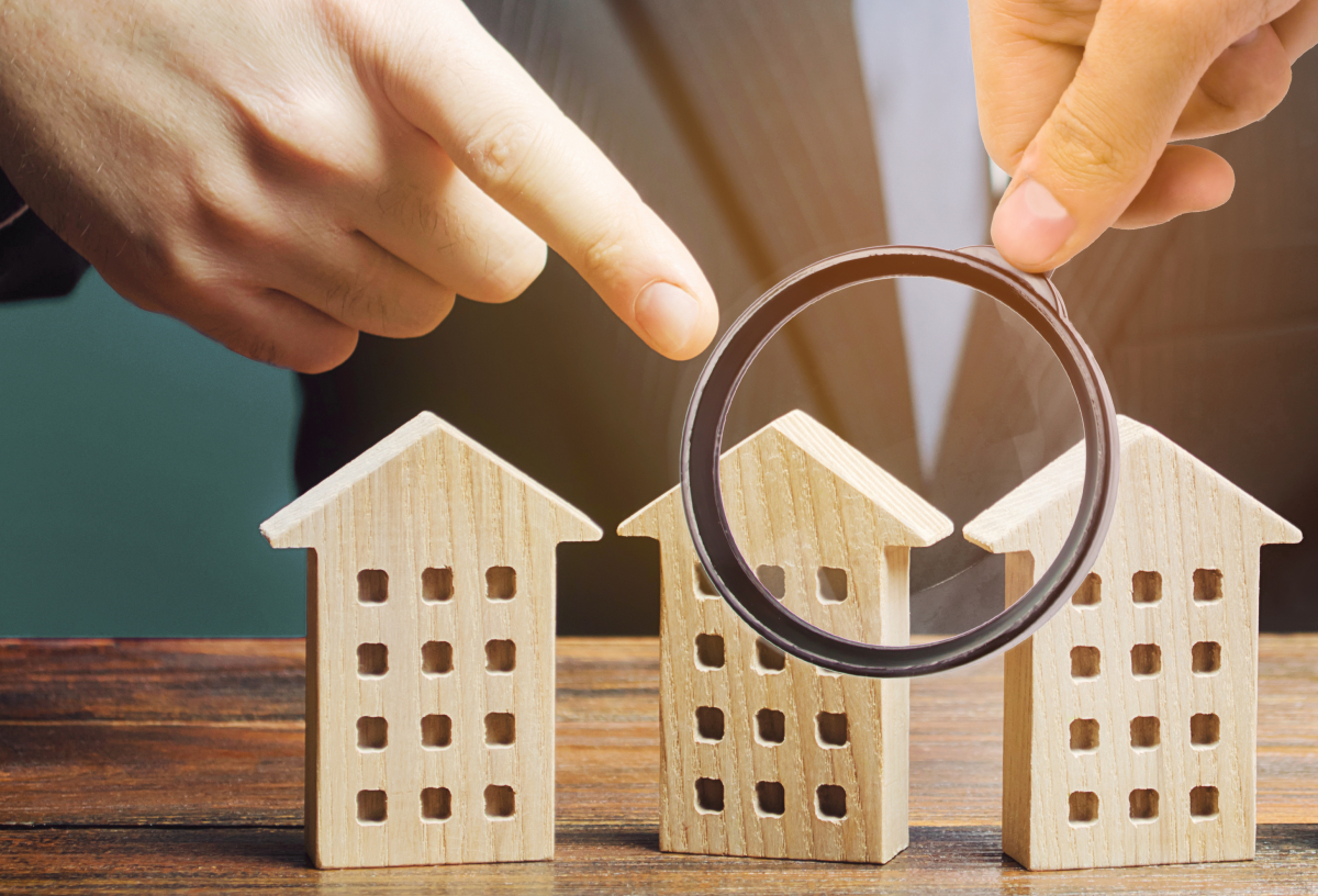 logement collectif ou individuel - Une personne passe des maison miniatures en bois à la loupe