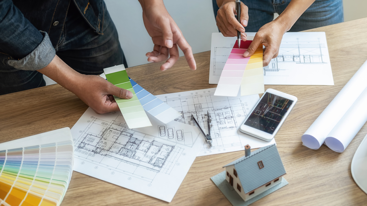 Le BEFA permet de personnaliser le bien immobilier à louer selon les besoins du locataire preneur BEFA Définition — Des personnes tenant des nuanciers autour d’un bureau couvert de plans de logements