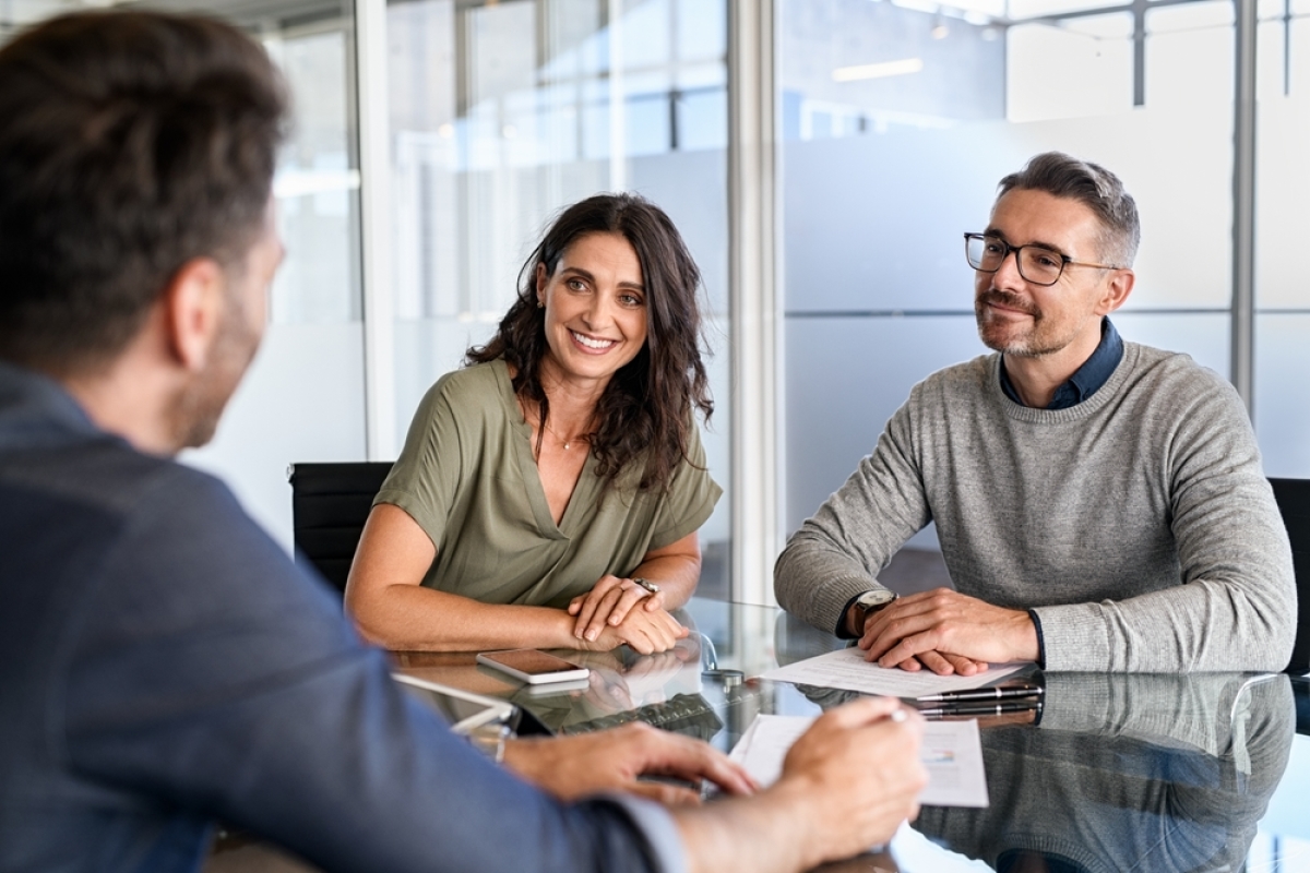 un couple de quadras souriants avec un conseiller financier