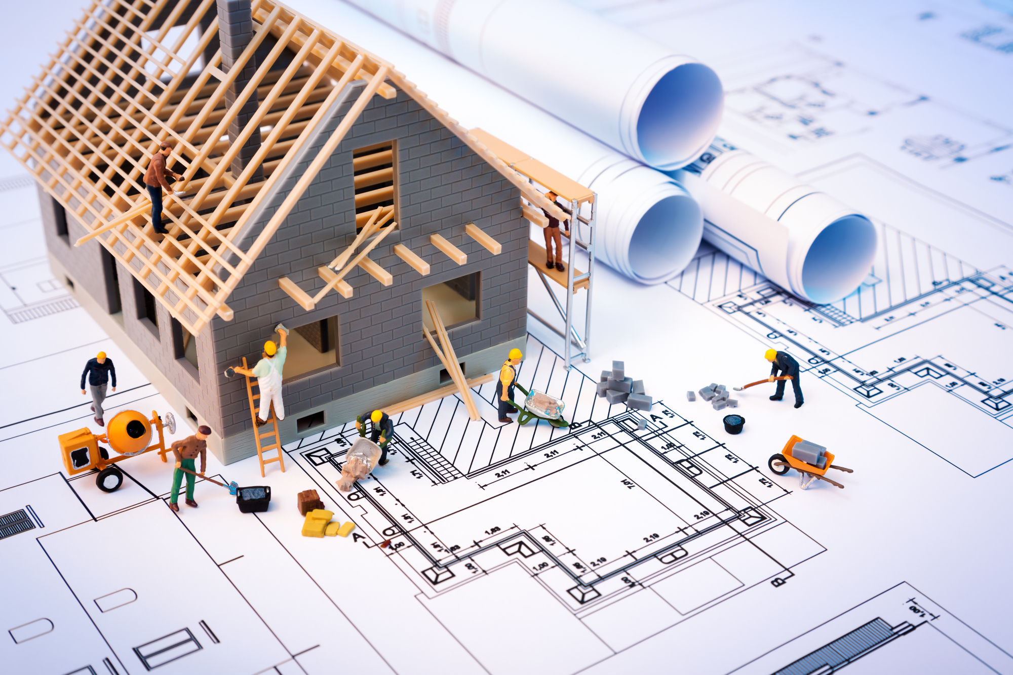 Une maquette de maison en construction posée sur un plan d'architecte