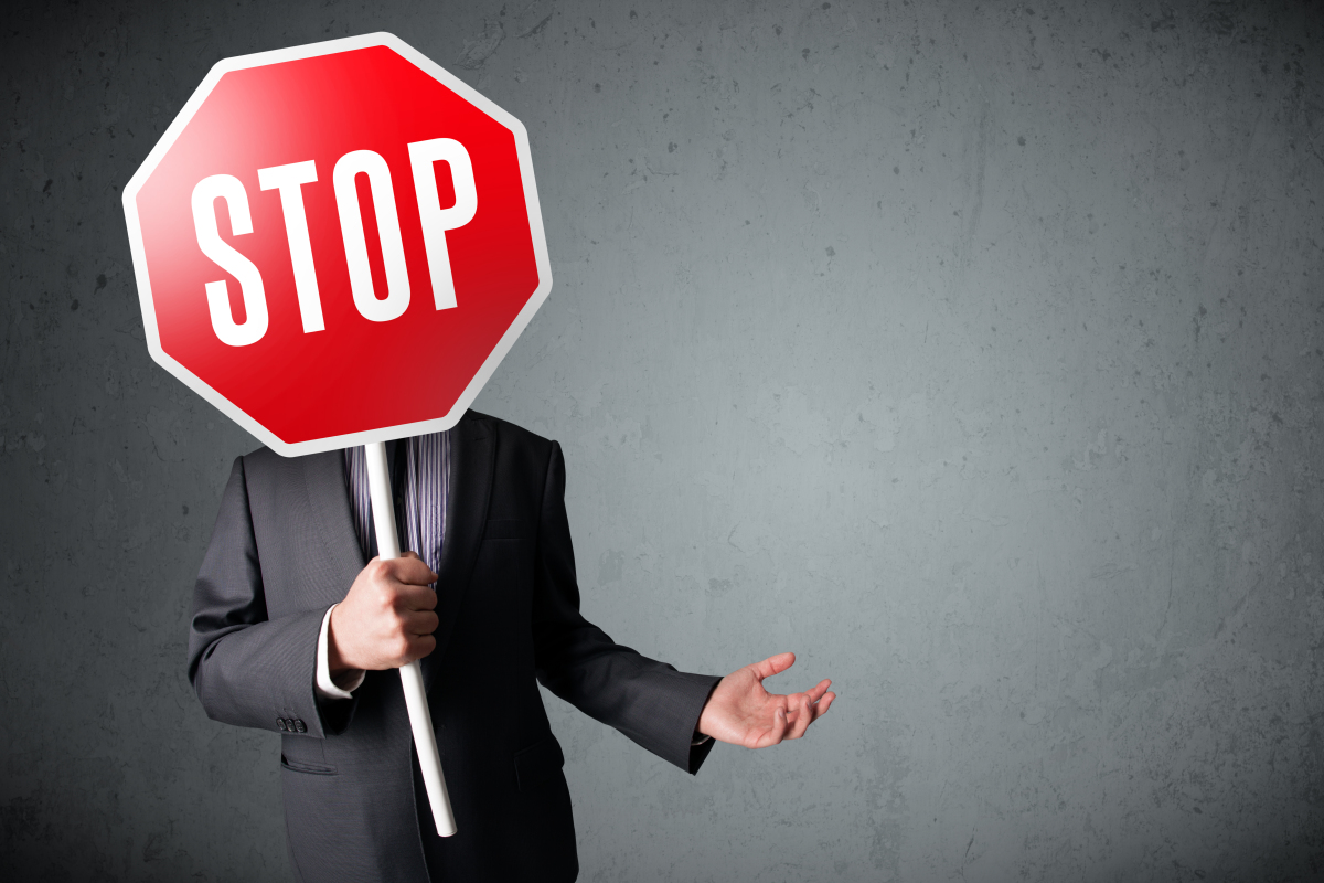  Un homme en costume tient un panneau "stop"