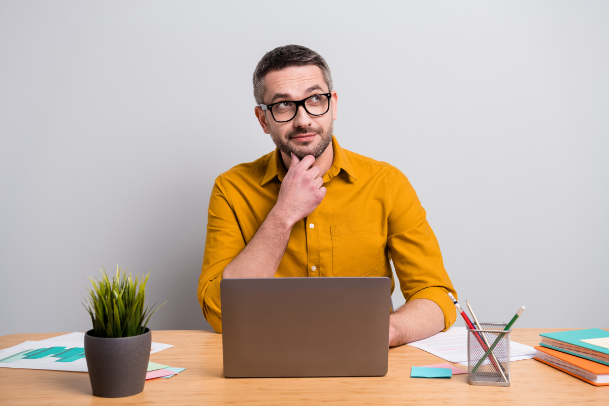 un homme en chemise jaune s’interroge devant un pc portable 