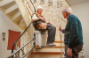 Une femme âgée utilisant un monte-escalier en regardant son conjoint