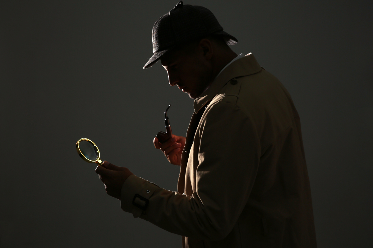 un courtier en immobilier neuf peut considérablement vous aider dans votre démarche d’achat en immobilier neuf à Bordeaux. un detective avec loupe dans la pénombre