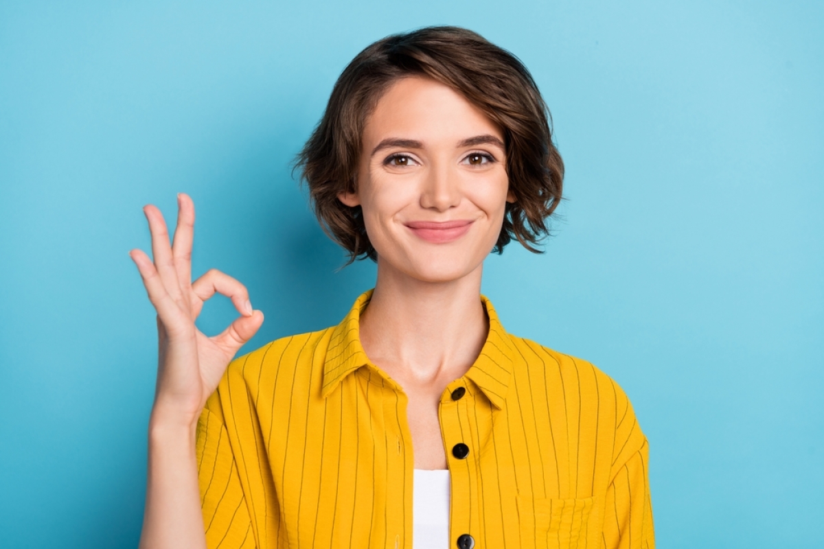 une femme faisant un signe ok sur fond bleu