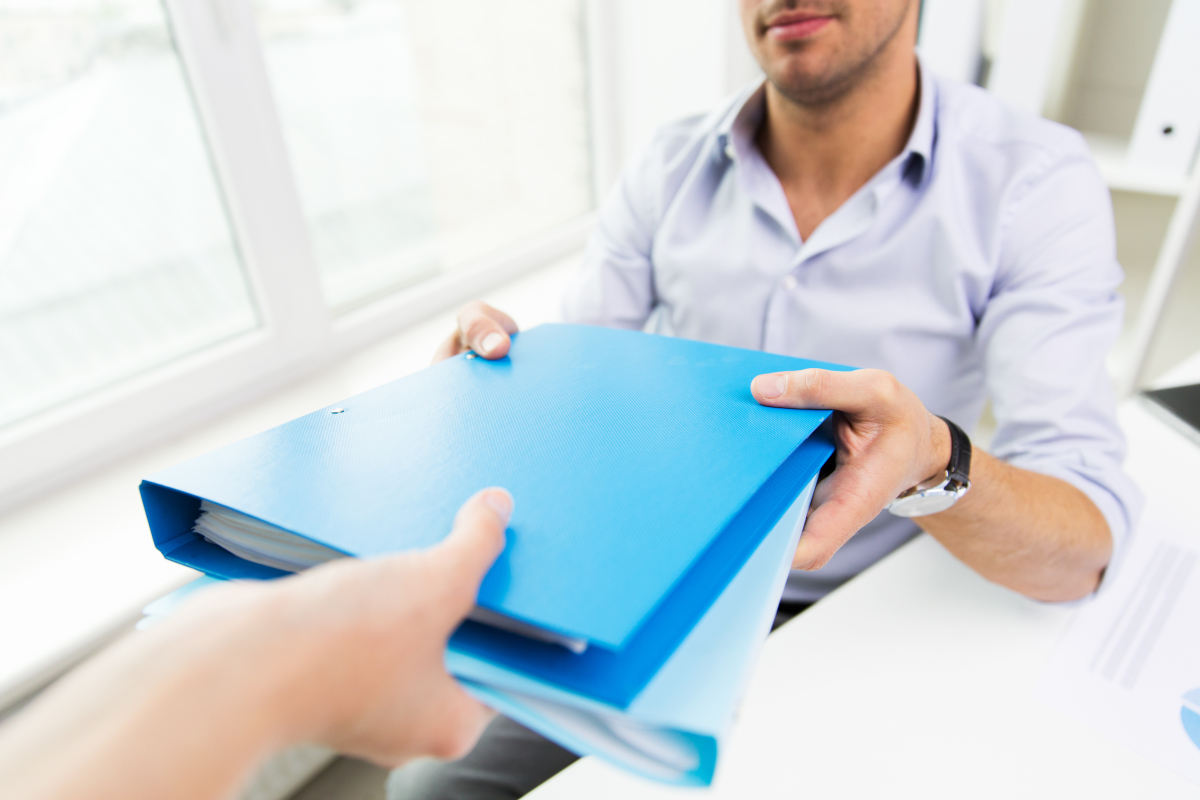 un homme tend un dossier bleu à une femme