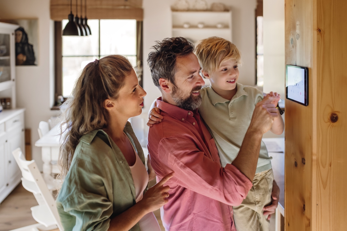 une famille devant une tablette numérique fixée au mur