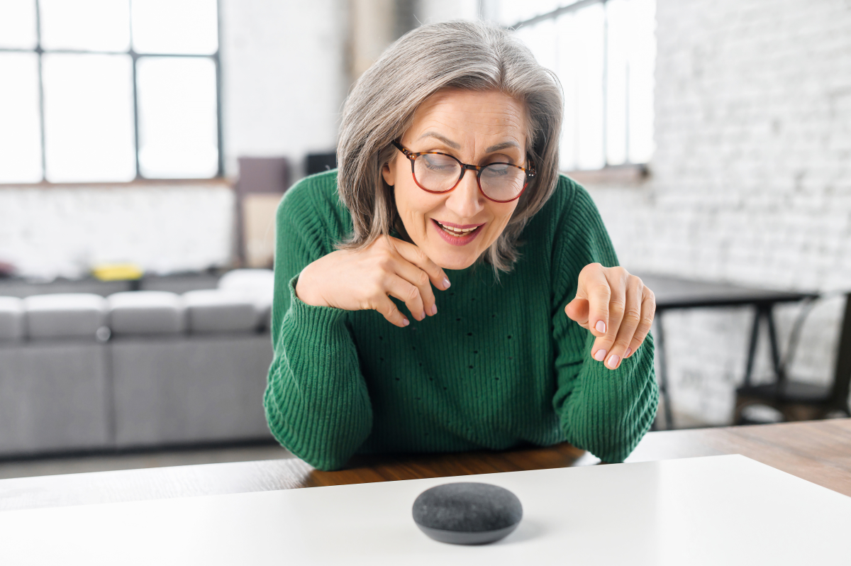 une femme aux cheveux gris parle à son assistant vocal