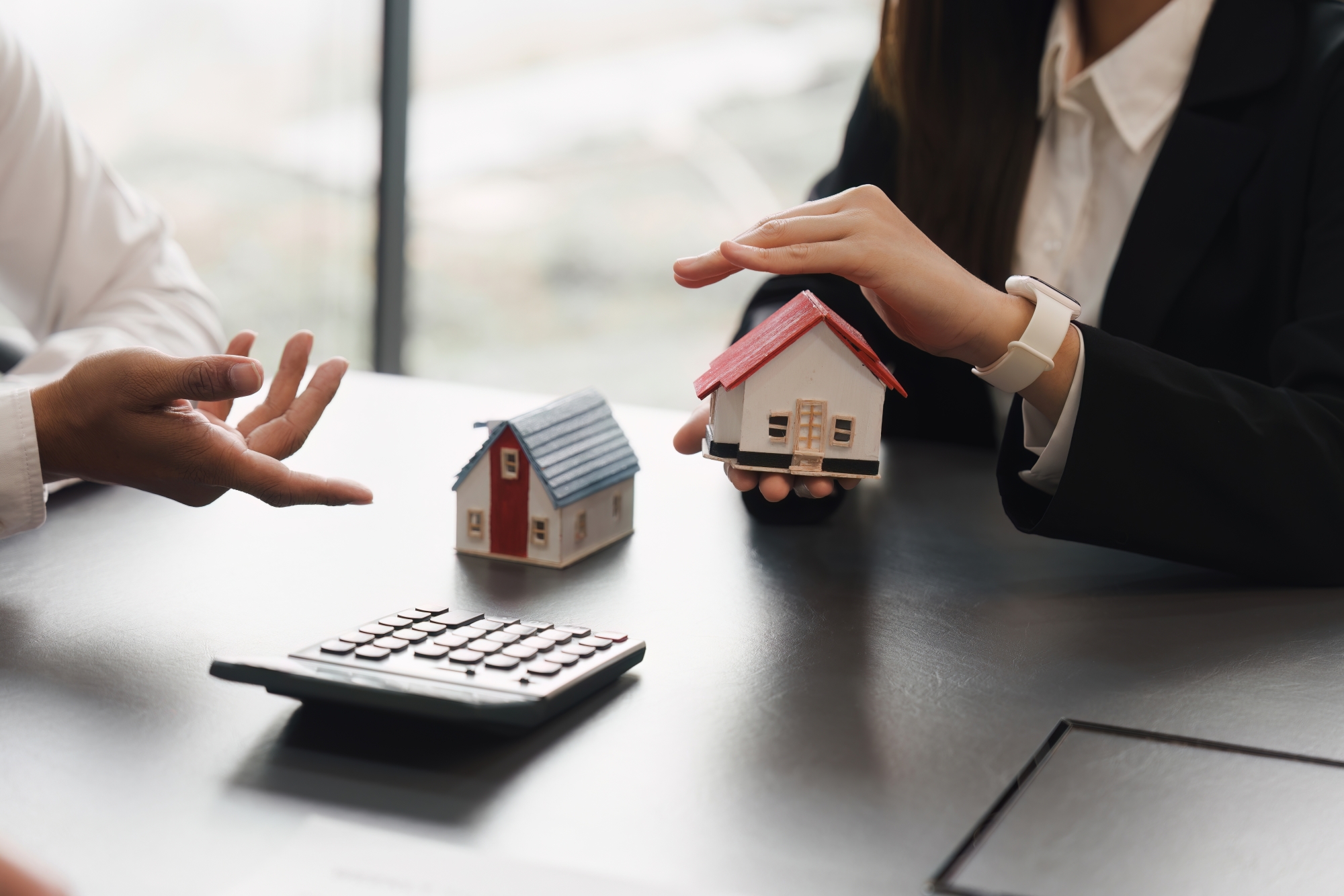 des mains d homme durant une négociation autour de petites maquettes de maisons