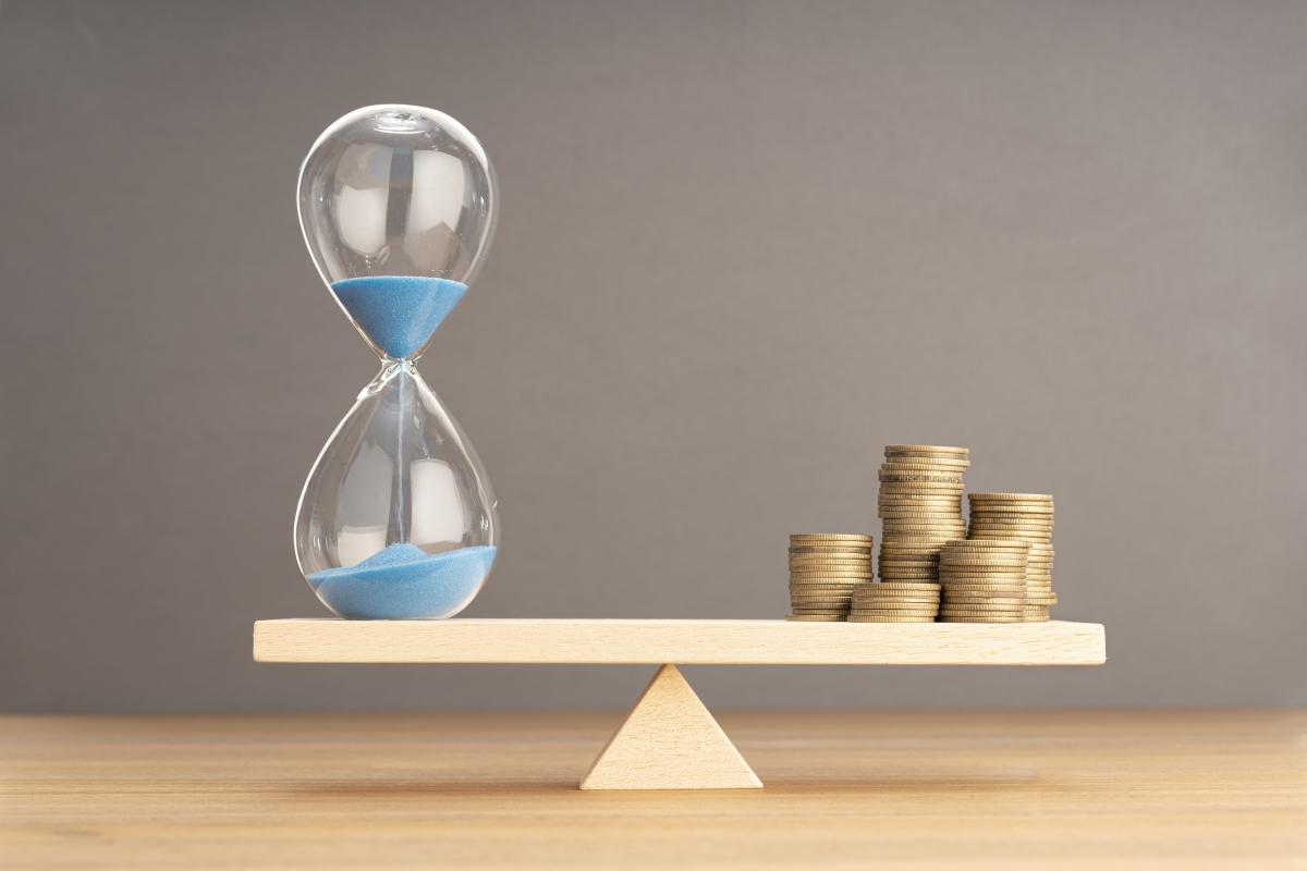 le meilleur moment pour renégocier son assurance emprunteur est le plus vite possible. un sablier et des tas de pièces sur une balance