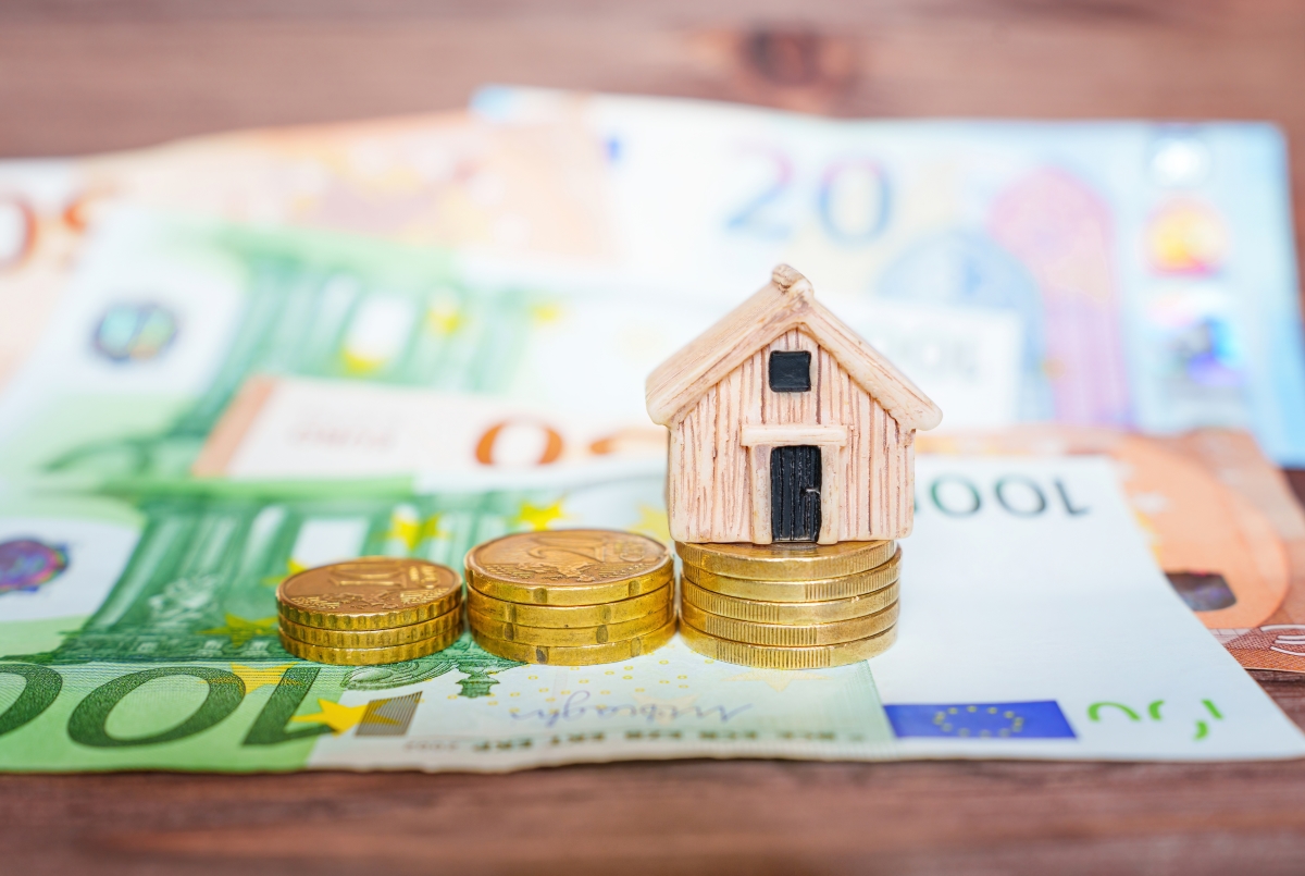 la baisse de l’apport personnel pour un crédit immobilier est une bonne nouvelle pour beaucoup de futurs proprietaires. une petite maquette de maison de bois sur des tas de pièces