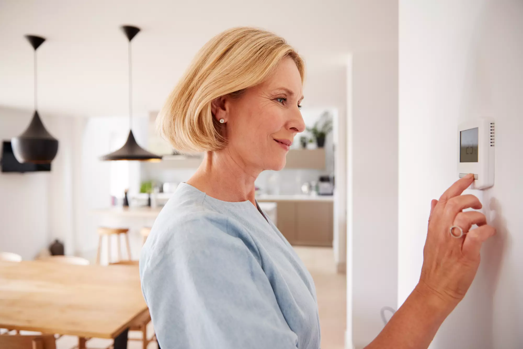 une femme programme son chauffage sur sa tablette