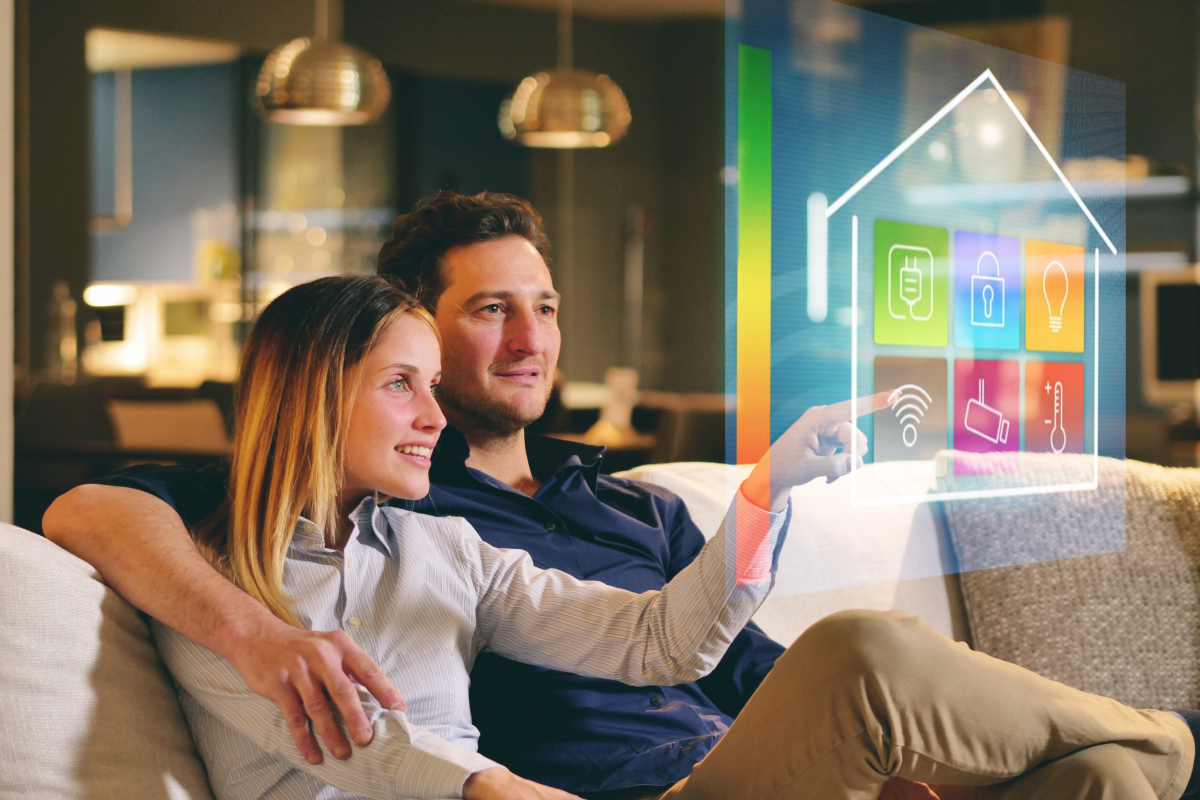 un couple sur un canapé qui regarde une image holographique des fonctions domotiques de leur appartement