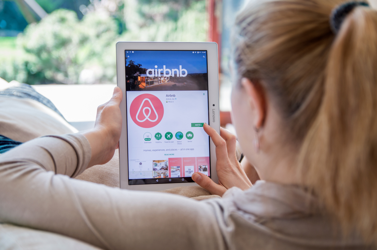une femme blonde consultant airbnb sur sa tablette