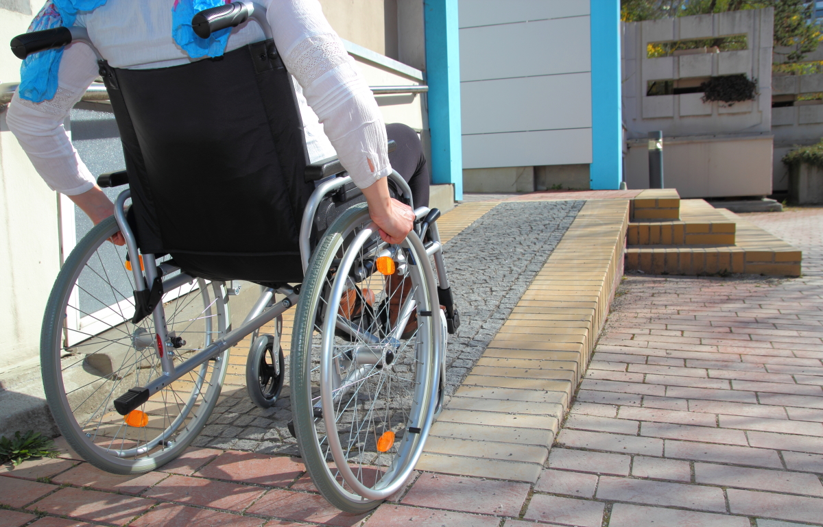 Réglementation PMR Logement — Une personne en fauteuil roulant emprunte une rampe d’accessibilité