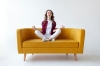 une femme en position du lotus sur son sofa